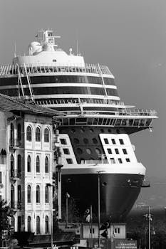 A cruise ship in a harbor, captured in a black and white photograph emphasizing its massive structure.