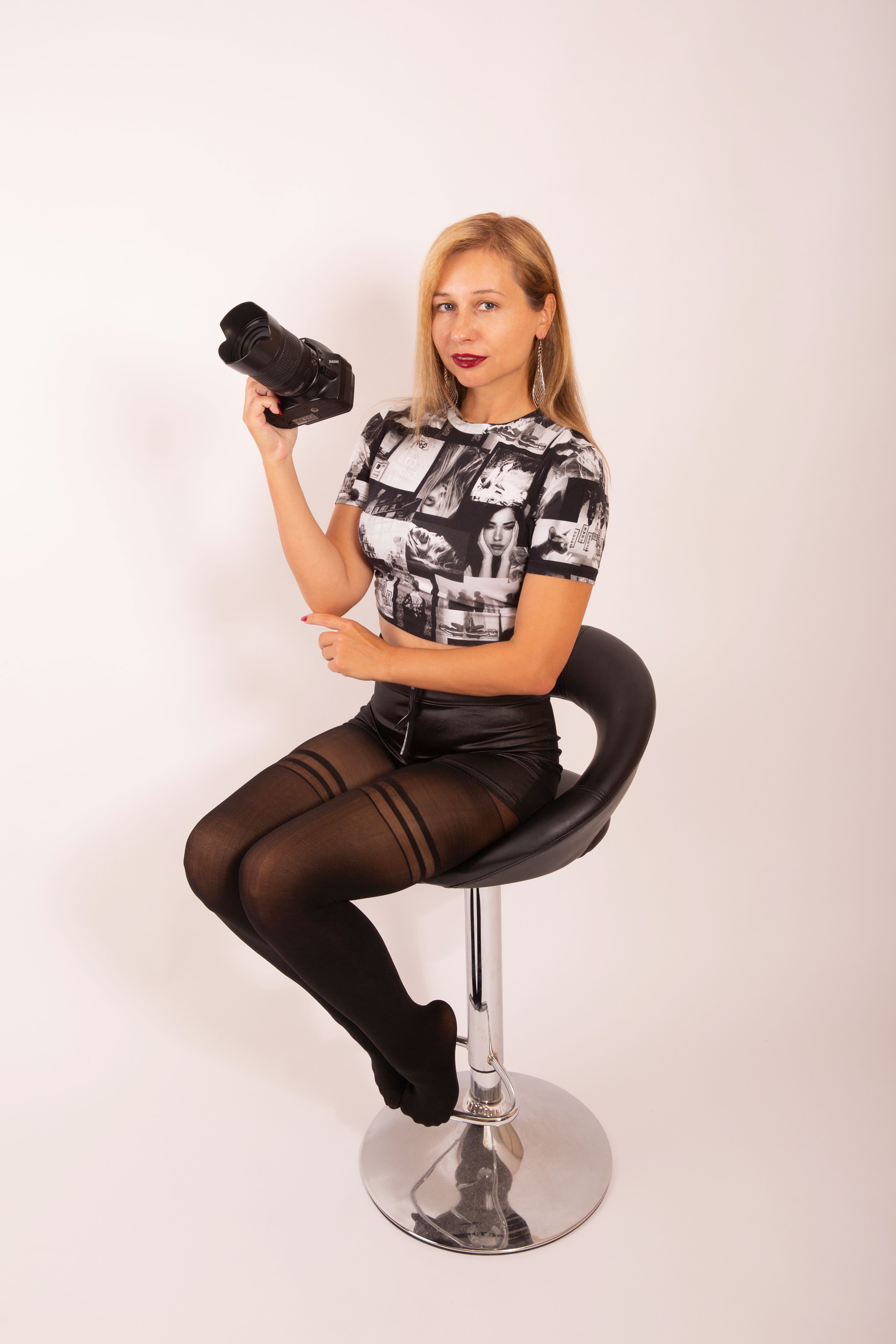 Woman sitting on a chair holding a camera in a photography studio.