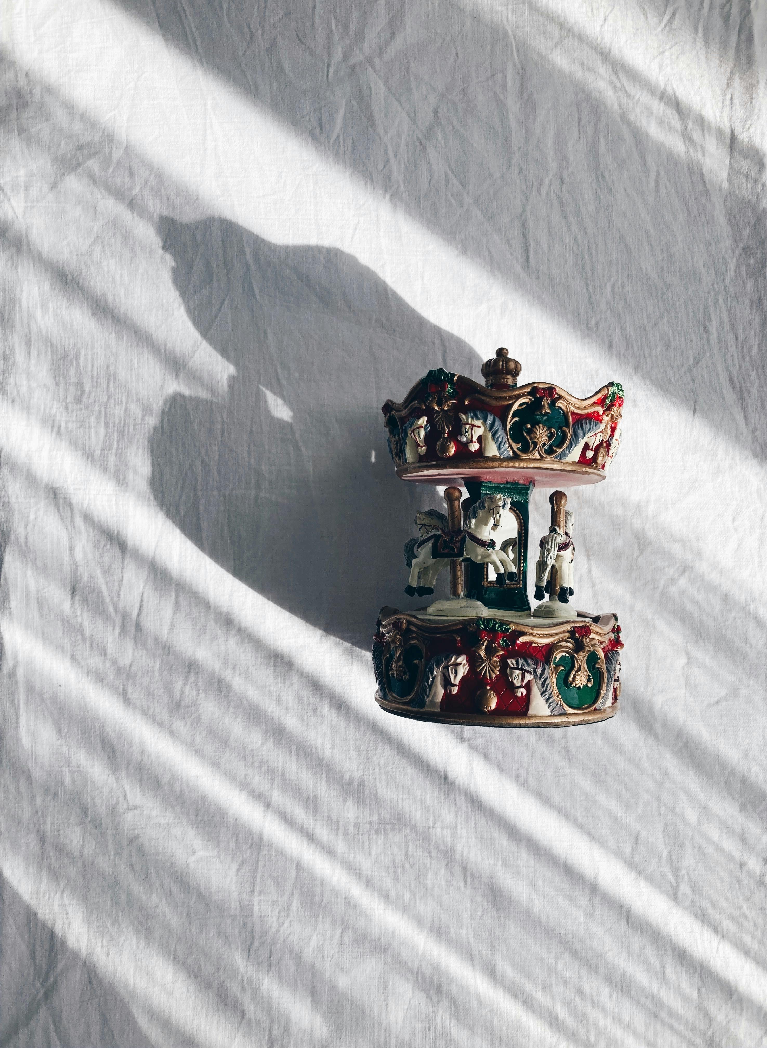 Charming vintage carousel figurine casting dramatic shadows in natural light.