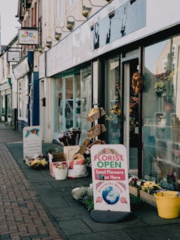 Charming flower shop facade with sidewalk displays, offering vibrant blooms in a bustling city street.