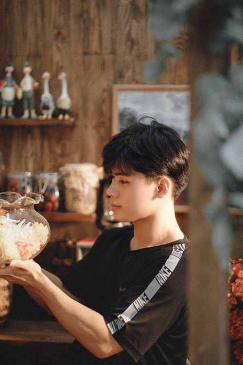 Free A young man with black hair examines a decorative glass bowl indoors. Stock Photo