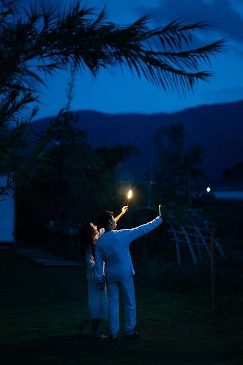 Man and Woman Standing Outside in the Dark with Candles