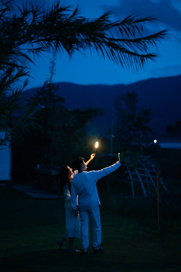 Man And Woman Standing Outside In The Dark With Candles