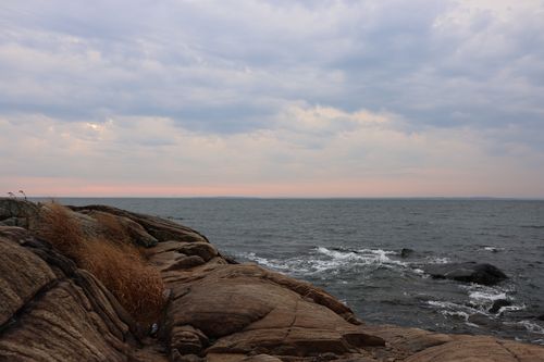 Free Peaceful seaside scene showcasing eroded rocks and gentle waves under a cloudy sky. Stock Photo