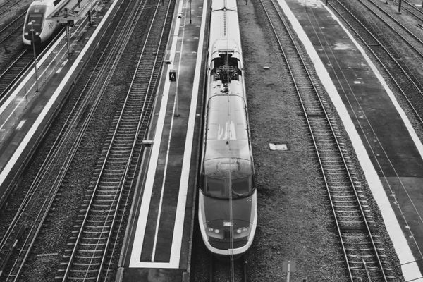 Black and white aerial view of a train at a railway station, showcasing urban transportation