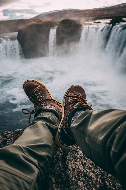 Personne Assise Sur Un Rocher Près De Cascades