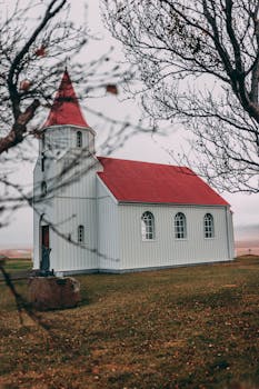 一座古色古香的乡村教堂，有着充满活力的红色屋顶，在秋天被树木环绕