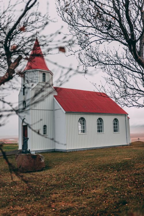 Free Scenic view of a quaint rural church with a vibrant red roof, surrounded by trees in autumn. Stock Photo