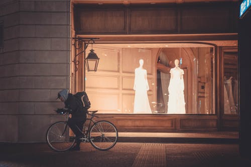 Man on a Bicycle in Front of the Window of a Wedding Dress Shop