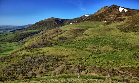 Explore the lush green slopes of Le Mont-Dore in Auvergne-Rhône-Alpes, France, under a clear blue sky.