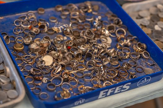 Close-up of assorted rings in a blue tray at a flea market in Izmir, Türkiye.