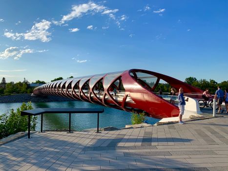 Peace Bridge in Calgary, Alberta over the Bow River on a sunny day with people enjoying the view.