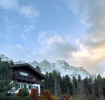 A tranquil Bavarian house nestled in a scenic forest with a stunning mountain backdrop.
