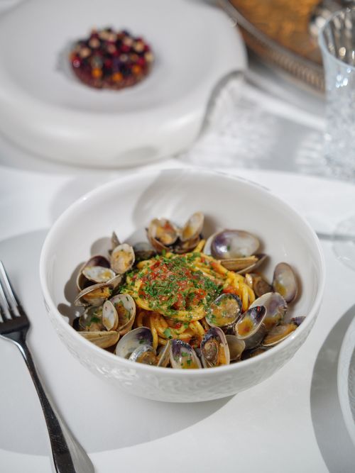 Free Delicious gourmet clam pasta dish served on a white table setting, perfect for fine dining photography. Stock Photo