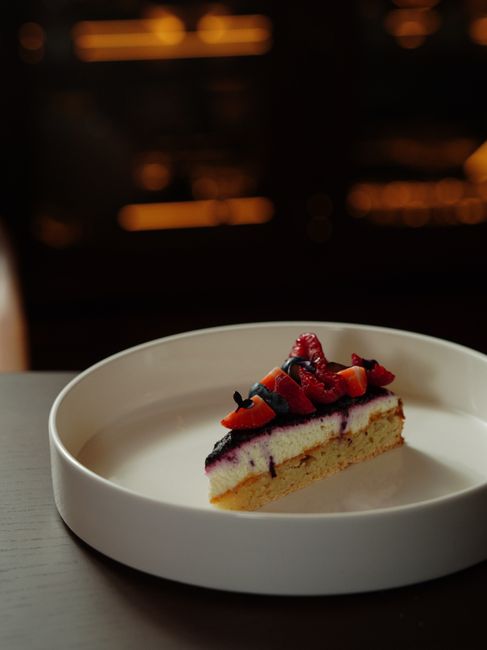 A slice of cheesecake topped with fresh berries in an elegant setting, perfect for dessert lovers.