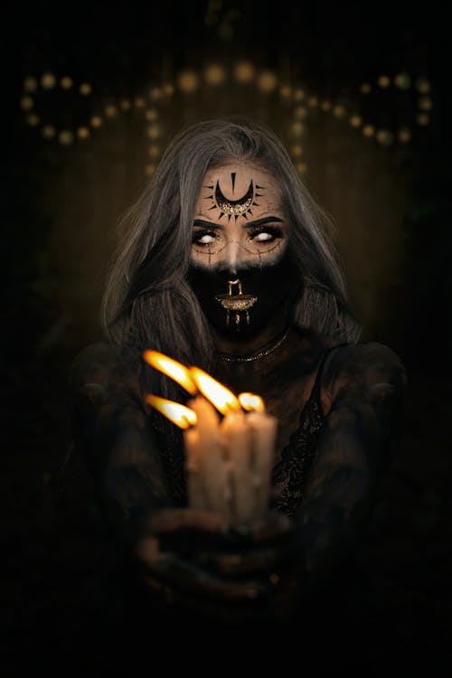 Woman in a Halloween Costume and Makeup Holding Burning Candles 