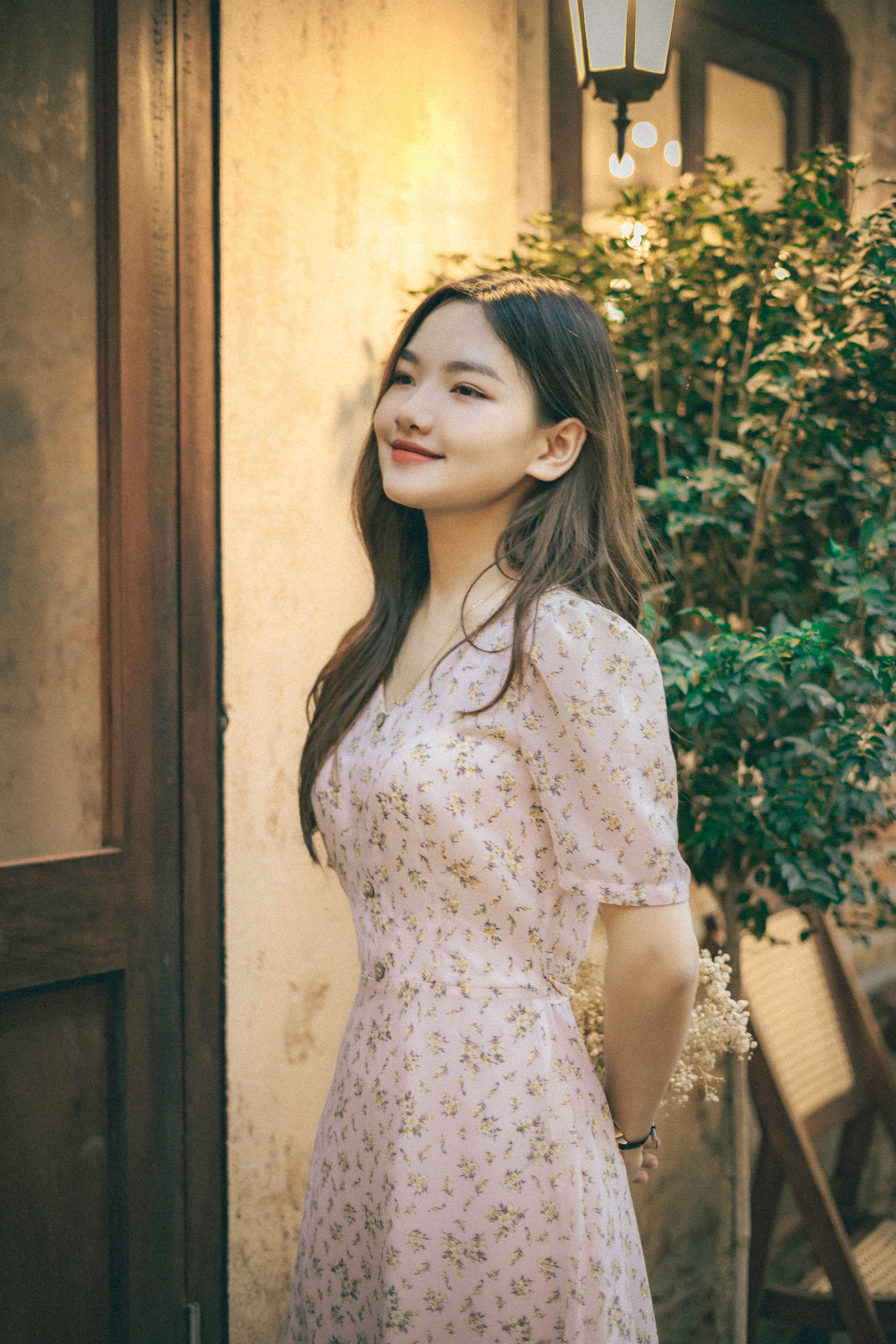 Young Woman in a Floral Dress Standing and Smiling · Free Stock Photo