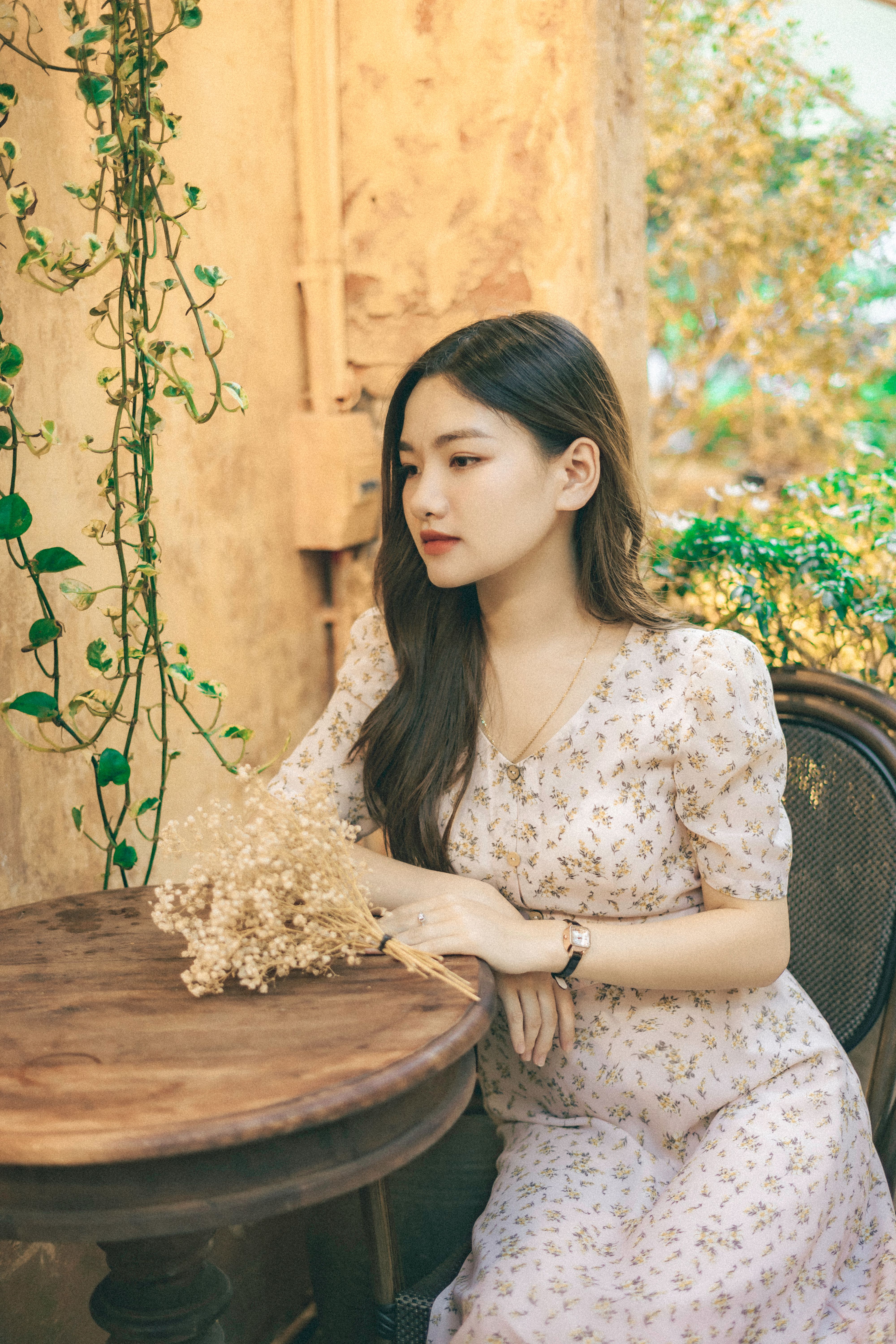 Young Woman in a Floral Dress Sitting at the Table · Free Stock Photo