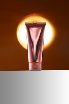 Close-up of a cosmetic tube against a warm, glowing background with ample copy space.