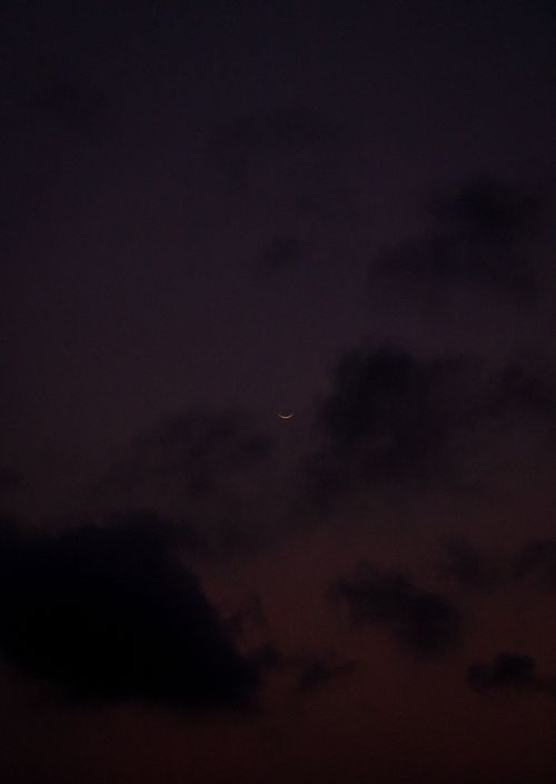 Free A peaceful twilight scene featuring a crescent moon amidst dark clouds, evoking calm and mystery. Stock Photo