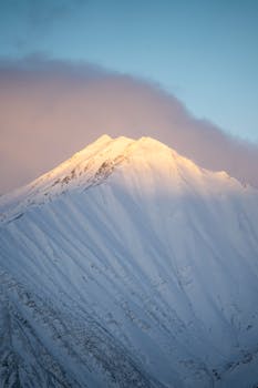 Captivating view of a snow-covered mountain peak glowing at sunset, under a clear sky.