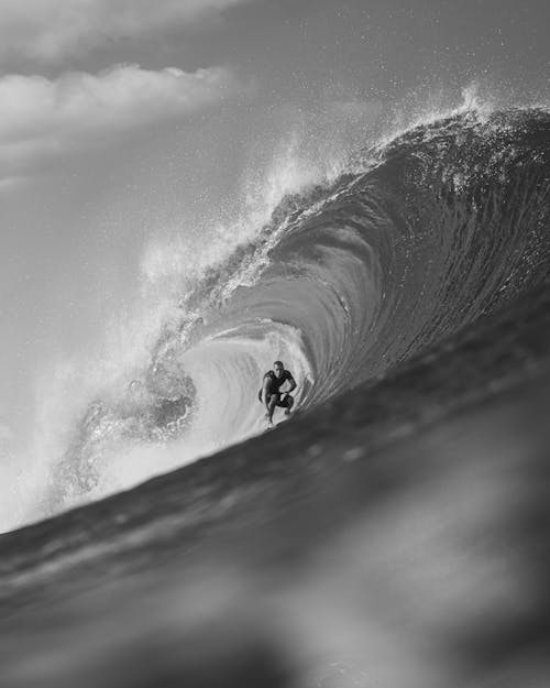 Black and White Photo of a Man Surfing on a Big Wave 