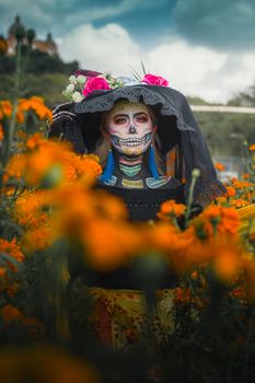A colorful portrait of a woman in Day of the Dead makeup amidst marigold flowers.