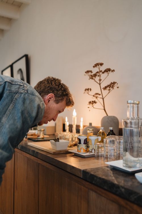 Free Man in a denim jacket bending over a candlelit table with drinks and decor in Amsterdam. Stock Photo