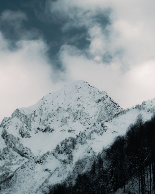 Free Majestic snow-covered mountain peak under a dramatic winter sky. Stock Photo