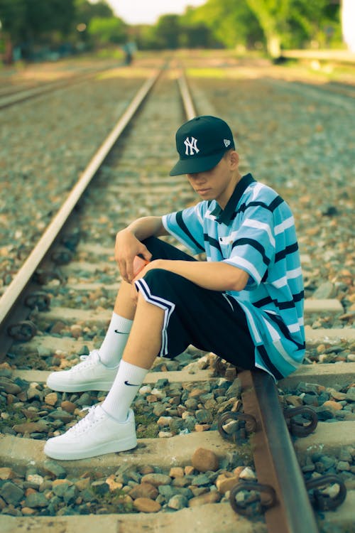 Man in Cap Sitting on Railway Track