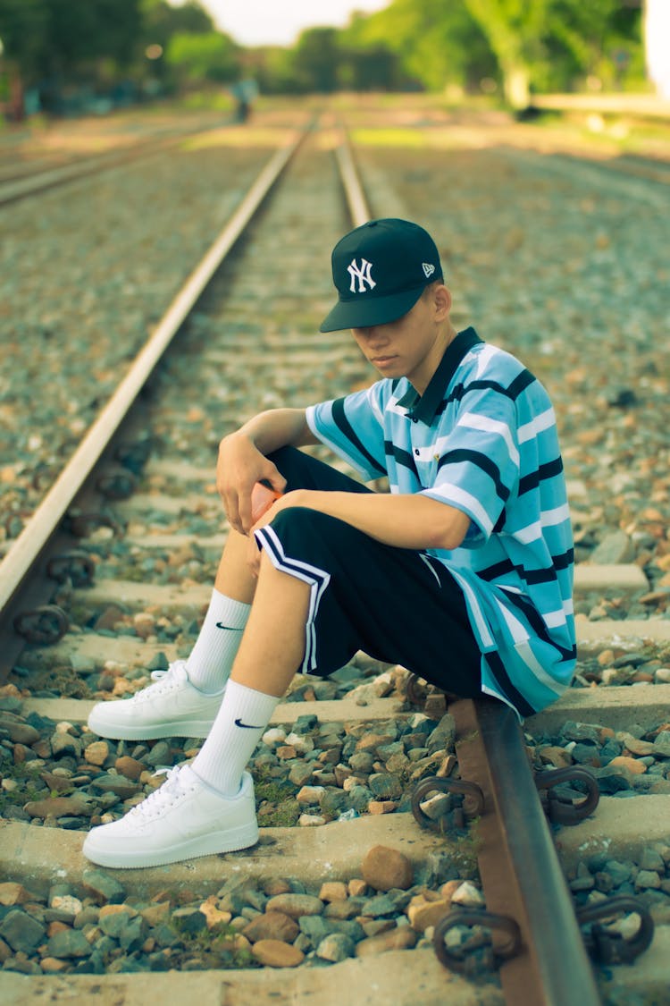 Man In Cap Sitting On Railway Track