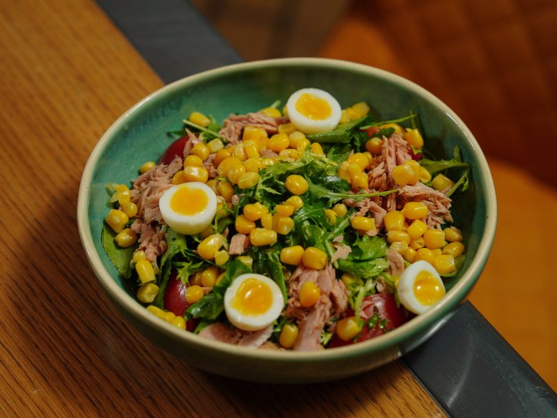 A vibrant bowl of tuna salad with corn and quail eggs for a healthy meal.