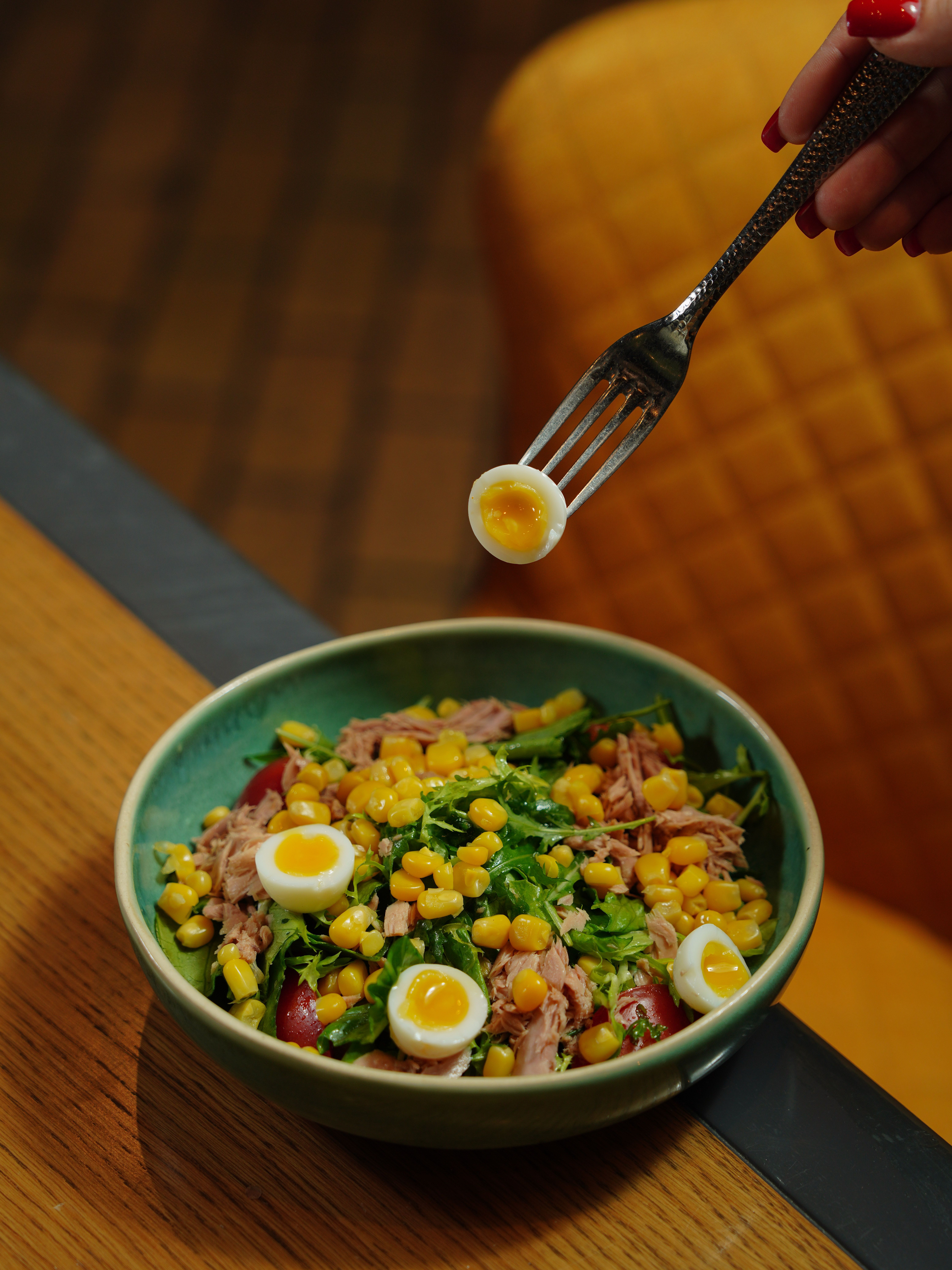Healthy salad with tuna, corn, greens, and quail eggs in a ceramic bowl.