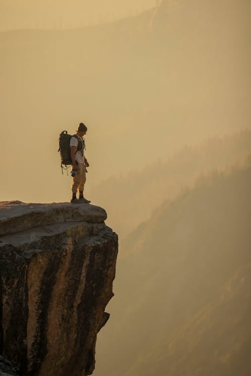 Man with a Backpack Standing on the Edge of a Cliff