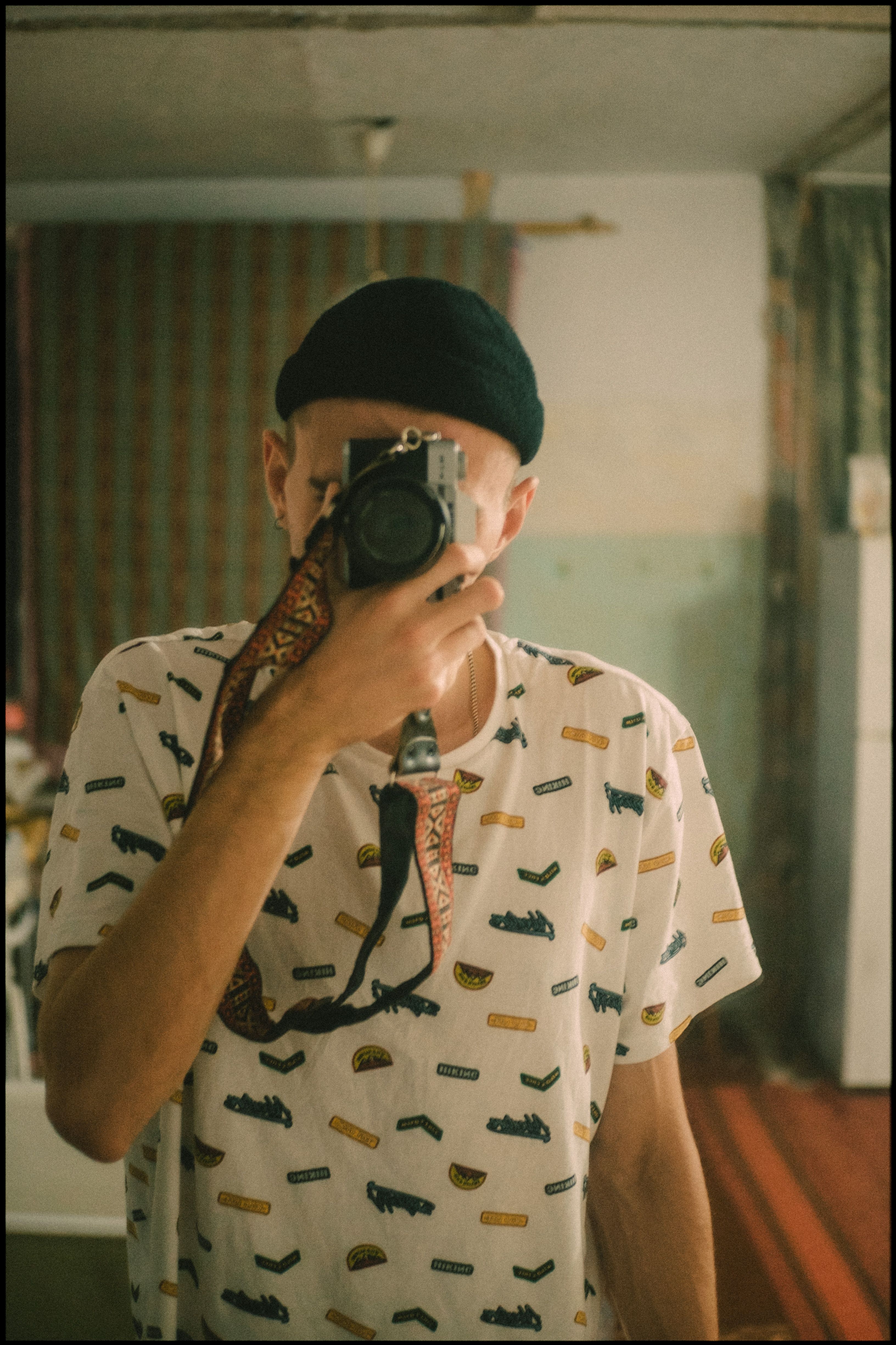 Man capturing a mirror selfie with a camera in vintage room.