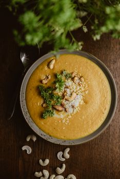 A rich and creamy cashew soup garnished with fresh herbs served in a bowl.