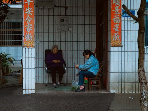 Women Sitting on Chairs in front of a Building in City 