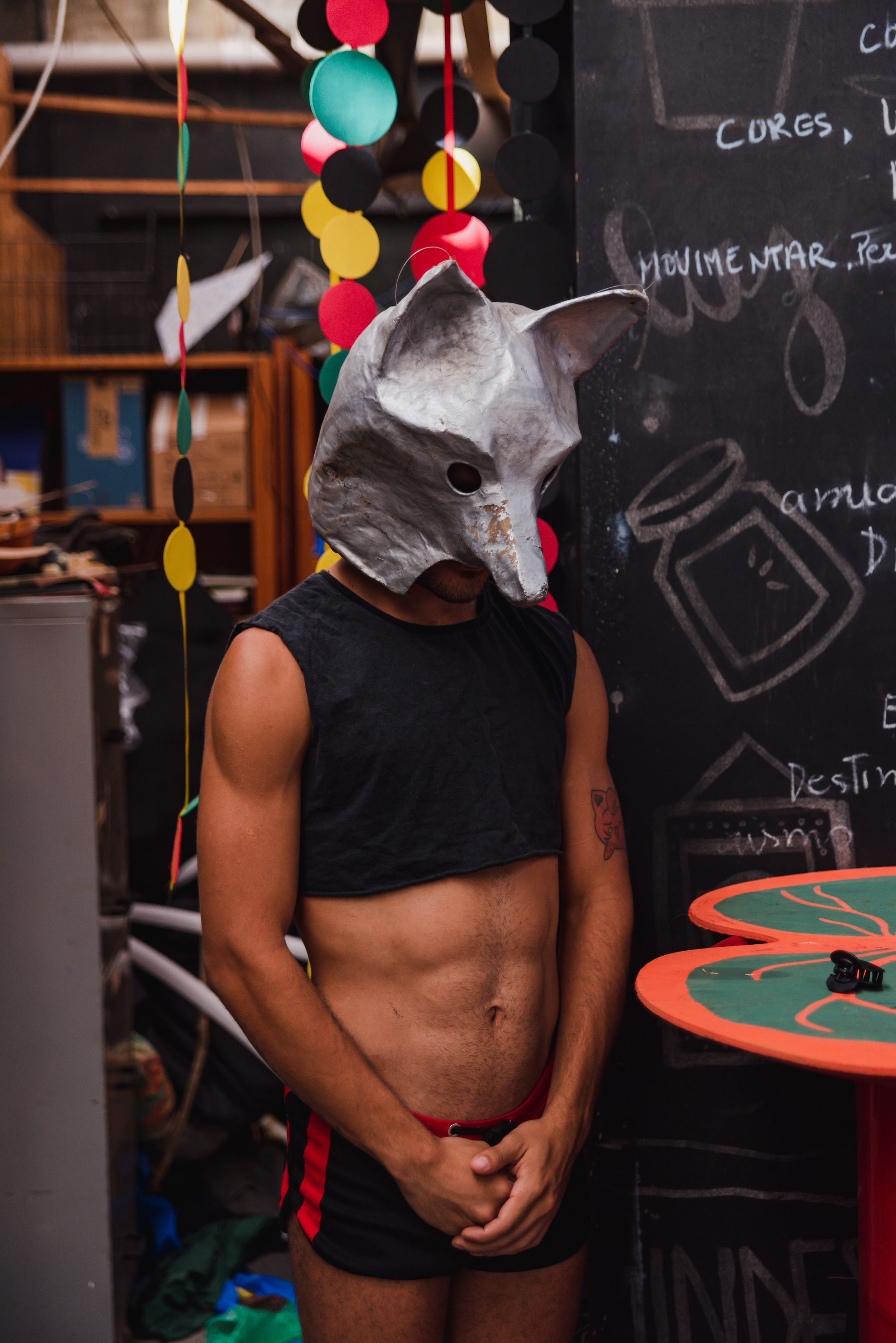 Man wearing a wolf mask and black top at a costume event indoors.