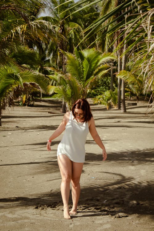 Woman Walking on Tropical Beach with Palm Trees behind