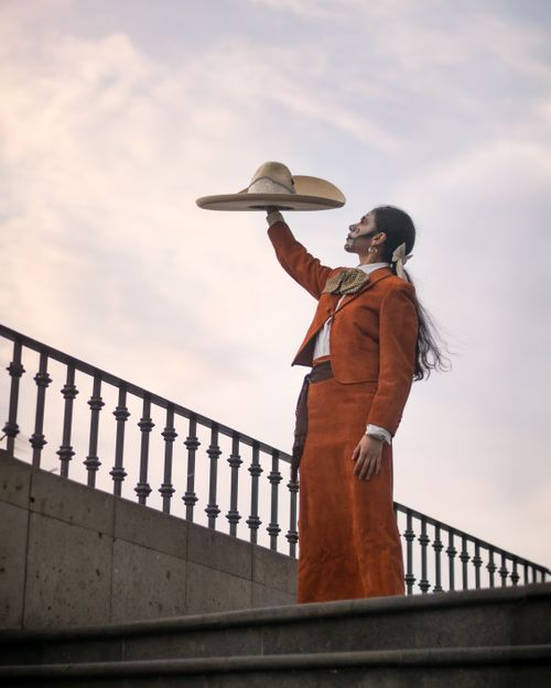 Free Model in traditional Mexican attire holding a sombrero against an urban backdrop. Stock Photo