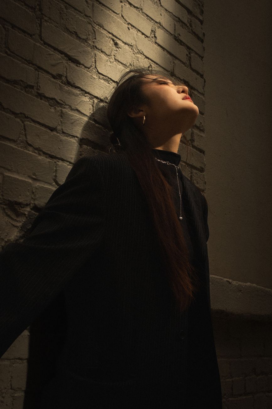 Stylish woman in a black blazer posing dramatically against a brick wall in Orlando.