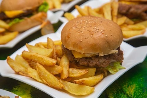 Free Delicious burger with cheese and fries served on a square plate. Perfect for fast food lovers. Stock Photo