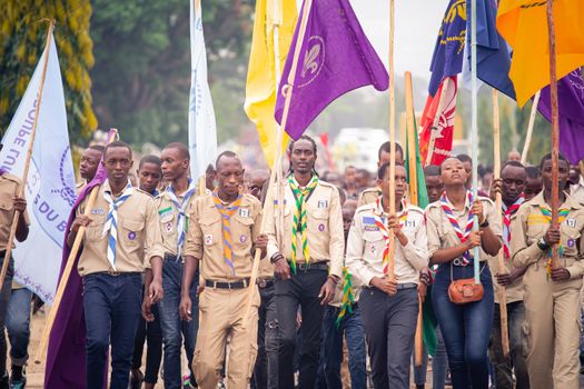 Young participants in uniform marching with flags in an outdoor rally event.