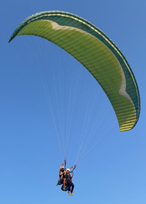 Free Two people enjoy paragliding against a clear blue sky, embracing adventure. Stock Photo