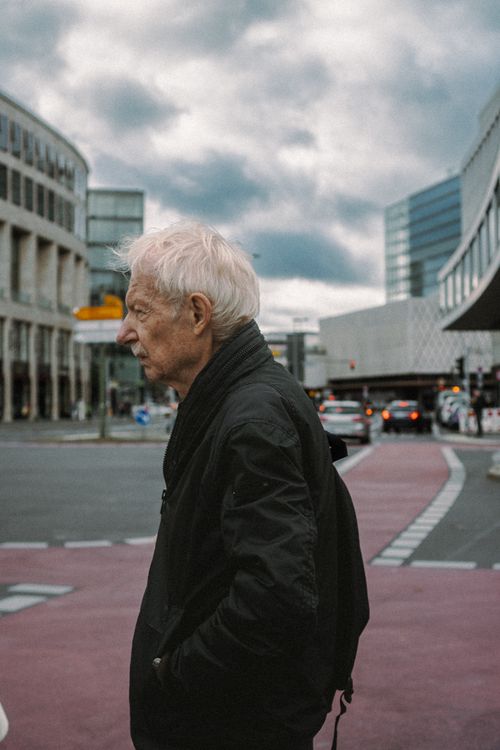 Free Profile of an elderly man walking in urban Berlin with modern architecture in the background. Stock Photo