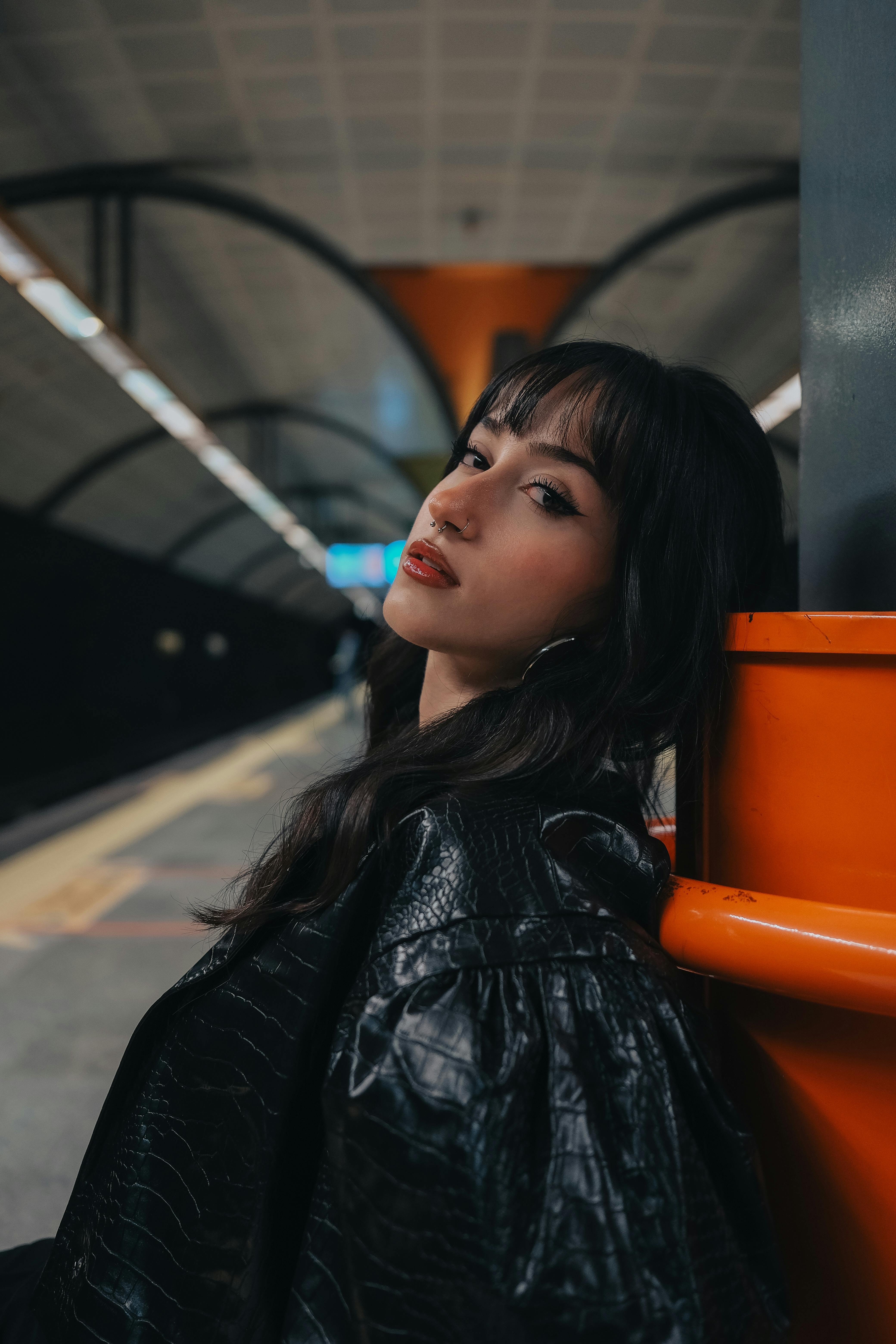 Woman in leather jacket leaning on pole in metro station