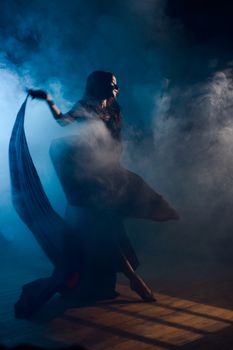 A captivating female dancer moves through fog in a moody, atmospheric setting.