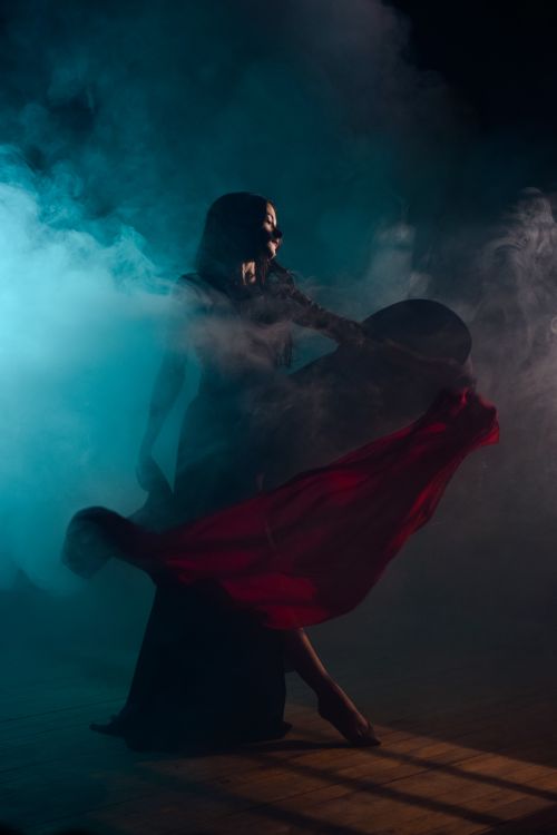 Free Woman in an elegant dress posing amidst swirling smoke, creating a dramatic effect. Stock Photo