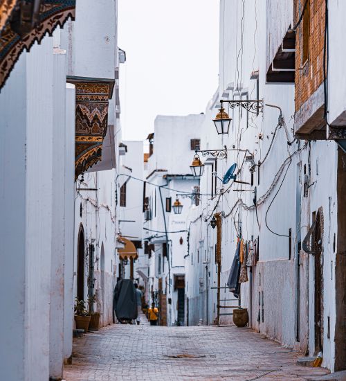 Free A picturesque narrow alley in a historic whitewashed medina with traditional architecture and lamps. Stock Photo