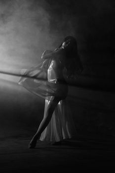 Captivating black and white ballet dancer posing gracefully amidst dramatic lighting.